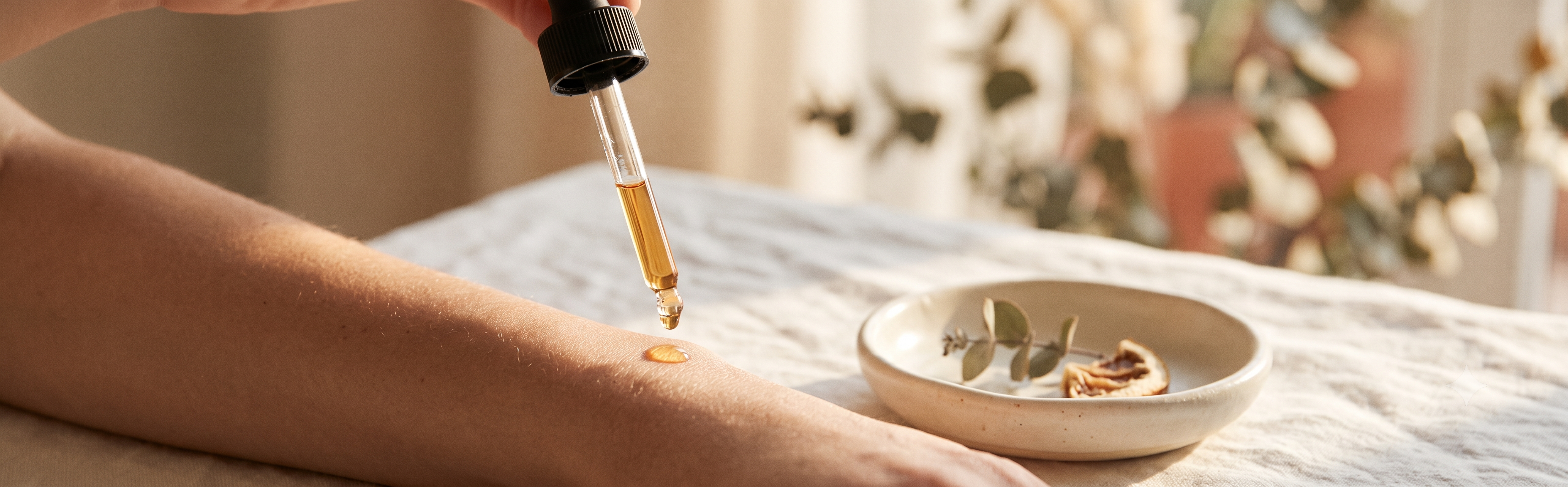 Vitamin-C-Serum wird als goldener Tropfen auf die Haut aufgetragen, warmes Morgenlicht, natürliche Pflegeatmosphäre